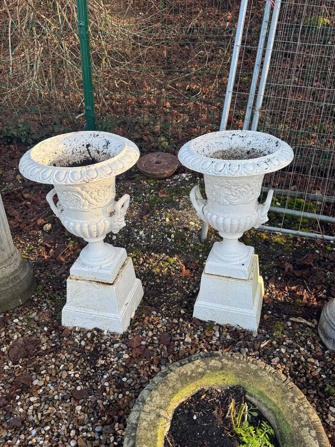 Lot 562 - A pair of cast iron garden urns and stands