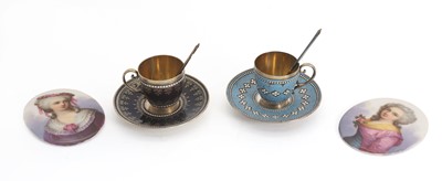 Lot 17 - A pair of silver and enamelled teacups and saucers
